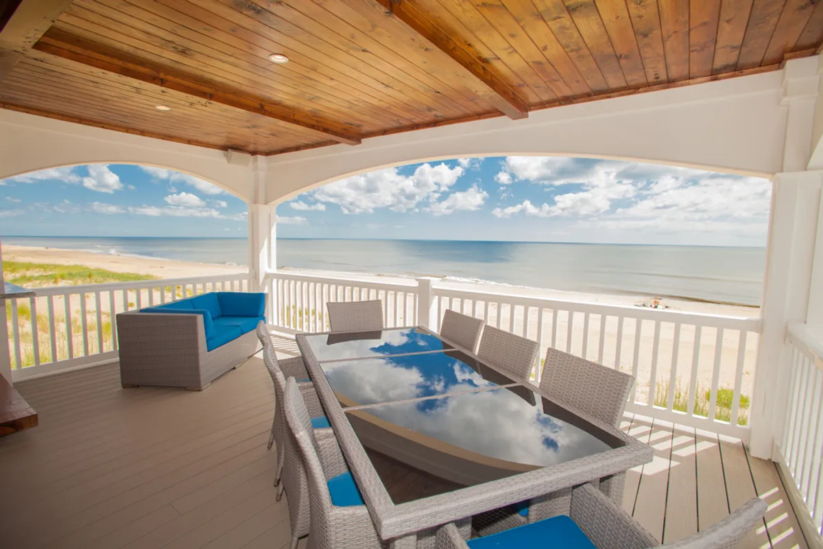 This image shows a serene outdoor seating and dining area with views of the ocean, featuring a spacious table surrounded by comfortable chairs. The setting is ideal for relaxing, socializing, and enjoying meals outdoors, all while taking in the natural beauty and tranquility of the surroundings. The warm lighting and inviting arrangement suggest a perfect spot to watch the sunrise or sunset and experience the pleasant Arizona climate.